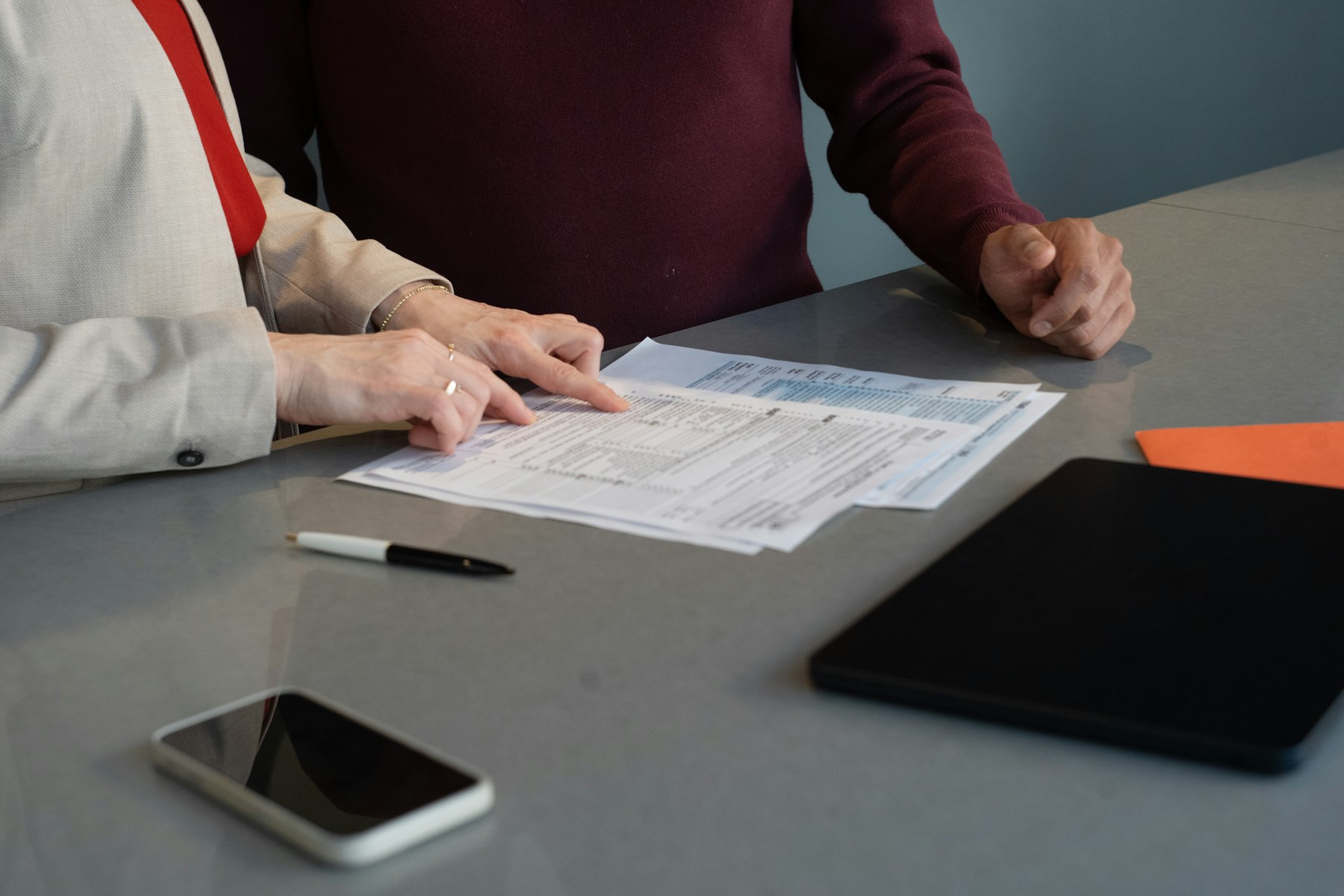 Two people reviewing printed documents together at a table